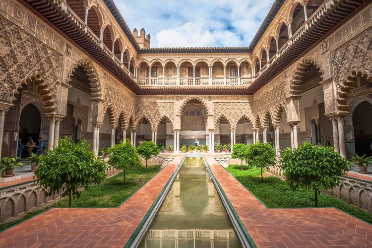 A stunning view of the Alcázar of Seville, showcasing its intricate Mudejar architecture and lush gardens with a blend of Islamic and Christian influences Alcazar Sevilla 2025.